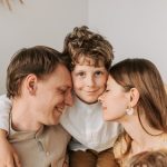 A joyful family moment with parents and their son embracing indoors.