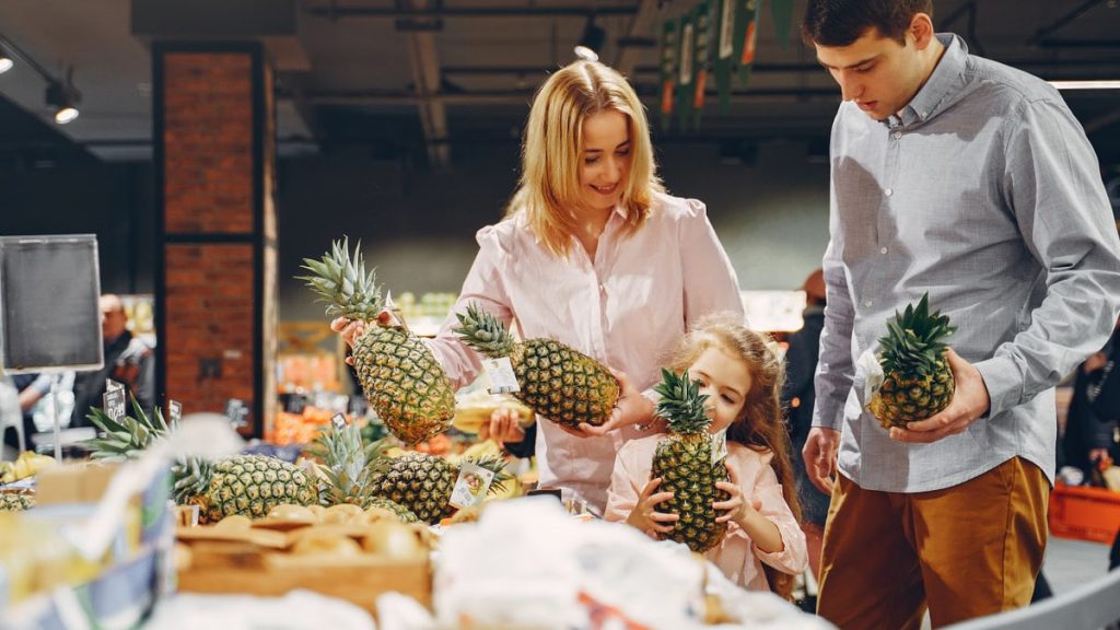 A happy family shopping for fresh pineapples together in a supermarket.