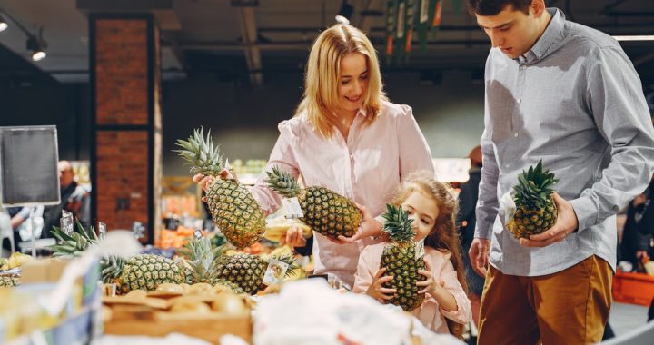 A happy family shopping for fresh pineapples together in a supermarket.